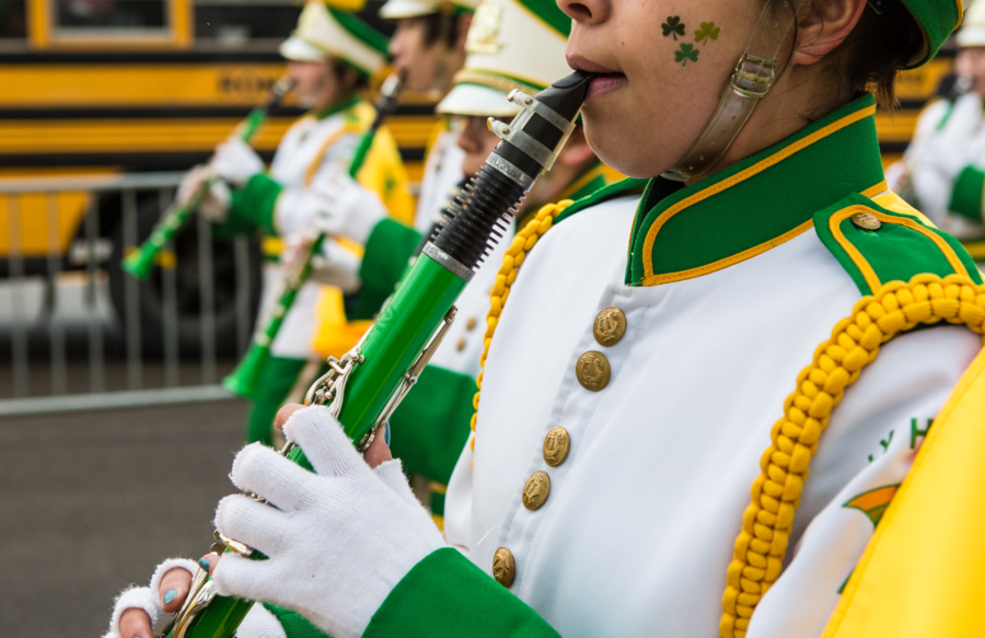 A young band member playing a flute marches in the annual St. Patrick's Day parade